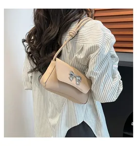 Dettaglio della borsa a spalla beige con fiocco in metallo argento e tracolla annodata