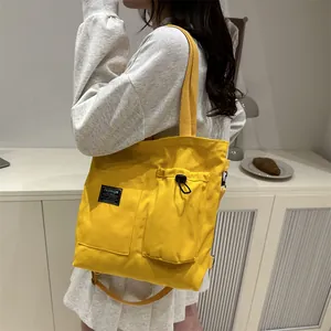Versatile yellow canvas tote bag with multi-pocket design and adjustable shoulder straps
