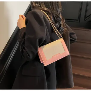 Detailansicht der rosa-beigen Umhängetasche mit goldener Kette auf einem schwarzen Blazer