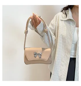 Dettaglio borsa a spalla beige con fiocco in metallo argento e tracolla con nodi