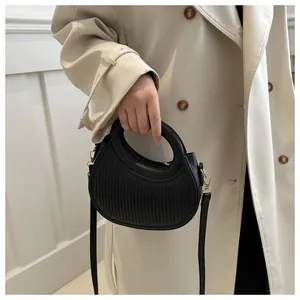 Detailed view of black leather handbag with vertical stripes and elegant gold hardware