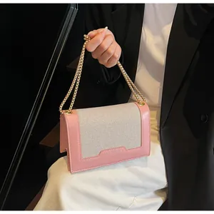 Detail der Schultertasche aus rosa Leder und Webstoff mit klobiger goldener Kette