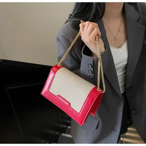 Detail der rot-beigen Schultertasche aus Canvas und Leder mit goldener Kette am Model getragen