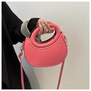 Detail view of pink half-moon handbag featuring vertical textured embossing and gold zipper