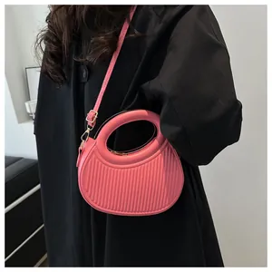 Detail of pink semi-circular handbag with vertical stripe embossing and golden hardware