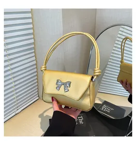 Vista dettagliata di una borsa baguette gialla minimalista con fiocco argento tenuta in mano