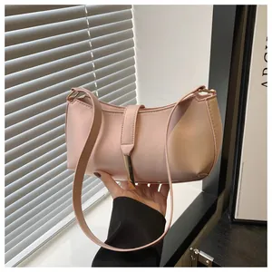 Close-up of pink crescent underarm bag with gold metal buckle and matte leather texture