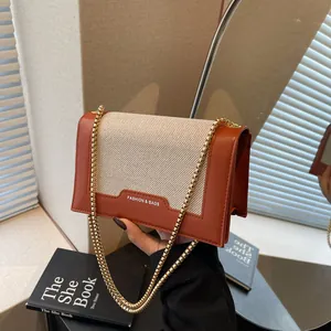 Schicke orangefarbene und beige Umhängetasche mit Goldkette und gewebten Einsätzen