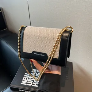 Minimalistische beige-schwarze Umhängetasche mit goldener Kette und stilvollem Kontrast
