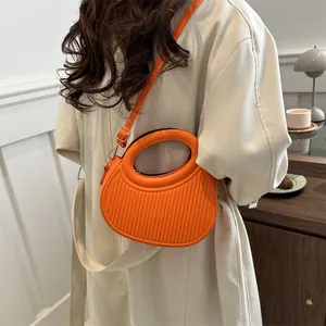 Bright orange crescent-shaped handbag with vertical stripes and golden hardware