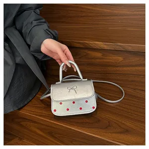 Detailansicht der silbernen Mini-Handtasche mit roten Punkten und Bogenstickerei