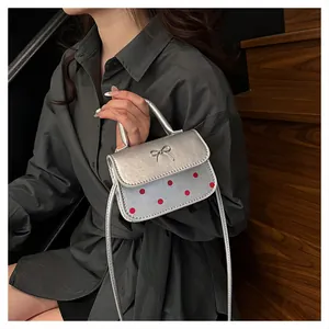 Detail der silbernen Schleifen-Handtasche mit roten Punkten und PU-Textur am Modell