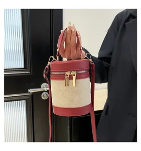 Detail of burgundy leather and beige canvas contrast stitching on cylinder bucket bag