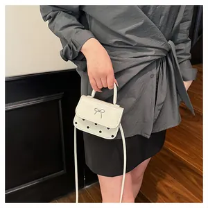 Detail der cremefarbenen Mini-Handtasche mit silberner Schleife und schwarzen Punkten