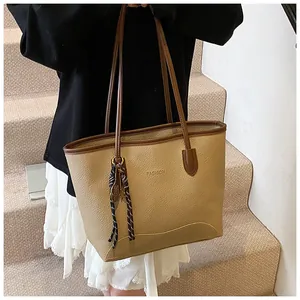 Detail of khaki leather tote bag with FASHION logo and woven tassel charm