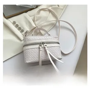 Detailweergave van geweven crèmekleurige bucket bag vergeleken met een smartphone