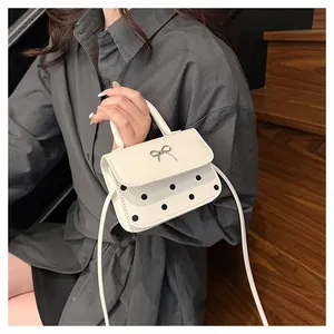 Detailansicht der cremefarbenen Mini-Punkt-Handtasche mit silberner Schleife und Griff