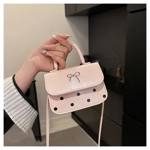 Detaillierte Makroansicht der rosa Lackleder-Handtasche mit Silberschleife und schwarzen Punkten