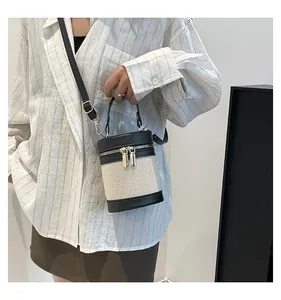 Detail of cylinder bucket bag featuring woven canvas and black leather trim for women
