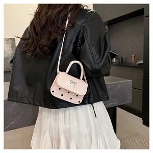 Rosa Mini-Umhängetasche mit silberner Schleife, getragen von einem Modell in modernem Raum