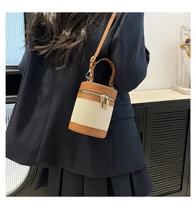 Detail of canvas bucket bag with brown leather trim and adjustable shoulder strap