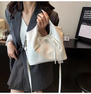 Detalle del bolso tipo cubo de cuero PU blanco con un lazo de encaje delicado y correa