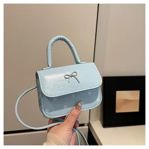 Detail der hellblauen Mini-Handtasche mit silberner Schleife und weißen Punkten