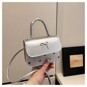 Nahaufnahme einer silbernen Handtasche mit Schleife, roten Punkten und Rundgriff