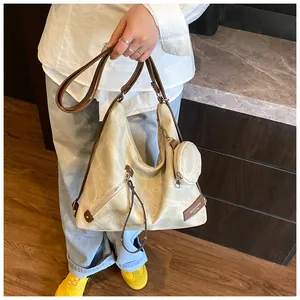 Detail view of beige tote bag with brown strap, side coin purse, and fashion label