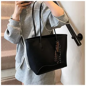 Detail of black pebbled leather tote bag with tennis racket charm worn by a model