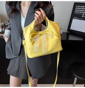 Detalle del bolso tipo cubo amarillo con un lazo de encaje blanco y correa ajustable
