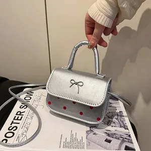 Mini Silber-Handtasche mit roten Punkten und Metallbogen am Griff getragen