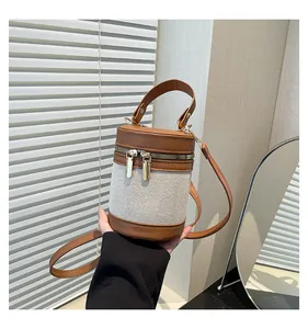 Detail view of contrast stitch bucket bag with gold zipper and textured fabric