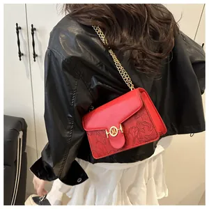 Dettaglio borsa in pelle rossa con goffratura floreale 3D e fibbia M dorata con catena