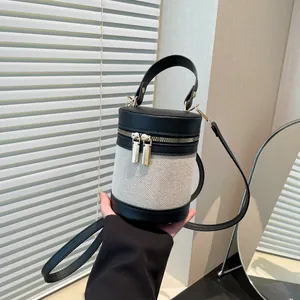 Μοντέρνα κυλινδρική τσάντα bucket από μπεζ καμβά και μαύρο δέρμα με χρυσό φερμουάρ