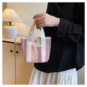 Detail van veelkleurige geweven tas met zilveren drukknoop en roze geruit patroon