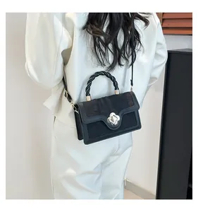 Detailed back view of a black crossbody bag with flower clasp on white clothing