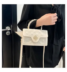 Detail of cream white handbag with floral gold clasp and twisted woven handle design
