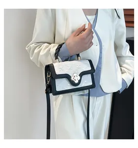 Detail of a chic two-tone handbag with a silver flower lock and a stylish braided handle