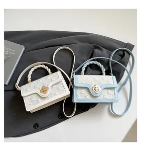 Detail of twisted rope handles and golden clover clasp on woven texture crossbody bags