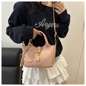 Close-up of pink litchi grain leather bucket bag with gold clasp and cute bear charm