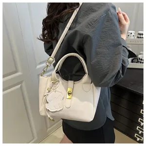 Detail of off-white lychee grain bucket bag with gold clasp and dog charm