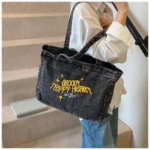 Detail of embroidered yellow lettering on vintage washed denim tote bag for daily commute