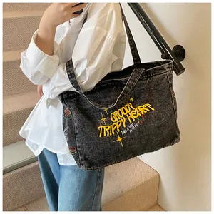 Detailed view of grey washed denim tote bag featuring yellow Groovy Trippy Heart embroidery