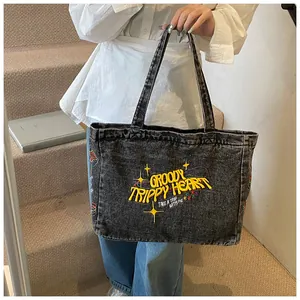 Detail of vintage denim tote bag featuring yellow embroidery and street style texture