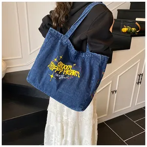 Detailed embroidery of GROOVY TRIPPY HEART text on dark blue denim tote bag surface