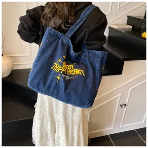 Detail of blue denim tote bag with yellow embroidered lettering and stars