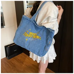 Close-up of blue denim tote bag featuring yellow embroidery and retro washed texture