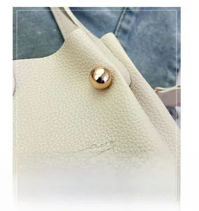 Close-up of golden spherical hardware on cream lychee-grain leather bucket bag
