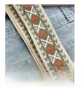 Close-up of geometric woven shoulder strap with ethnic diamond patterns on denim